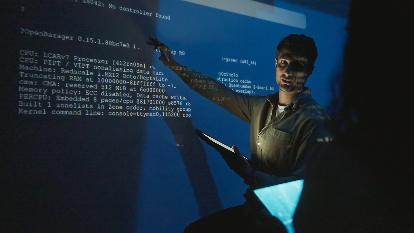 An engineer pointing at system code displayed on a large screen, illustrating AI engineering and enterprise system design.